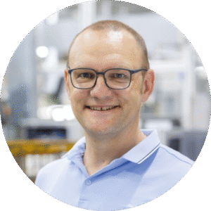 Porträtfoto einer Person mit Brille in moderner Arbeitsumgebung als Testimonial